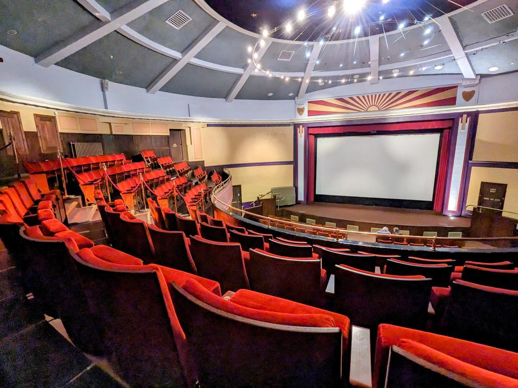 Interior of a Hippodrome Cinema, showing red seats facing a large blank screen, with decorative ceiling lights.