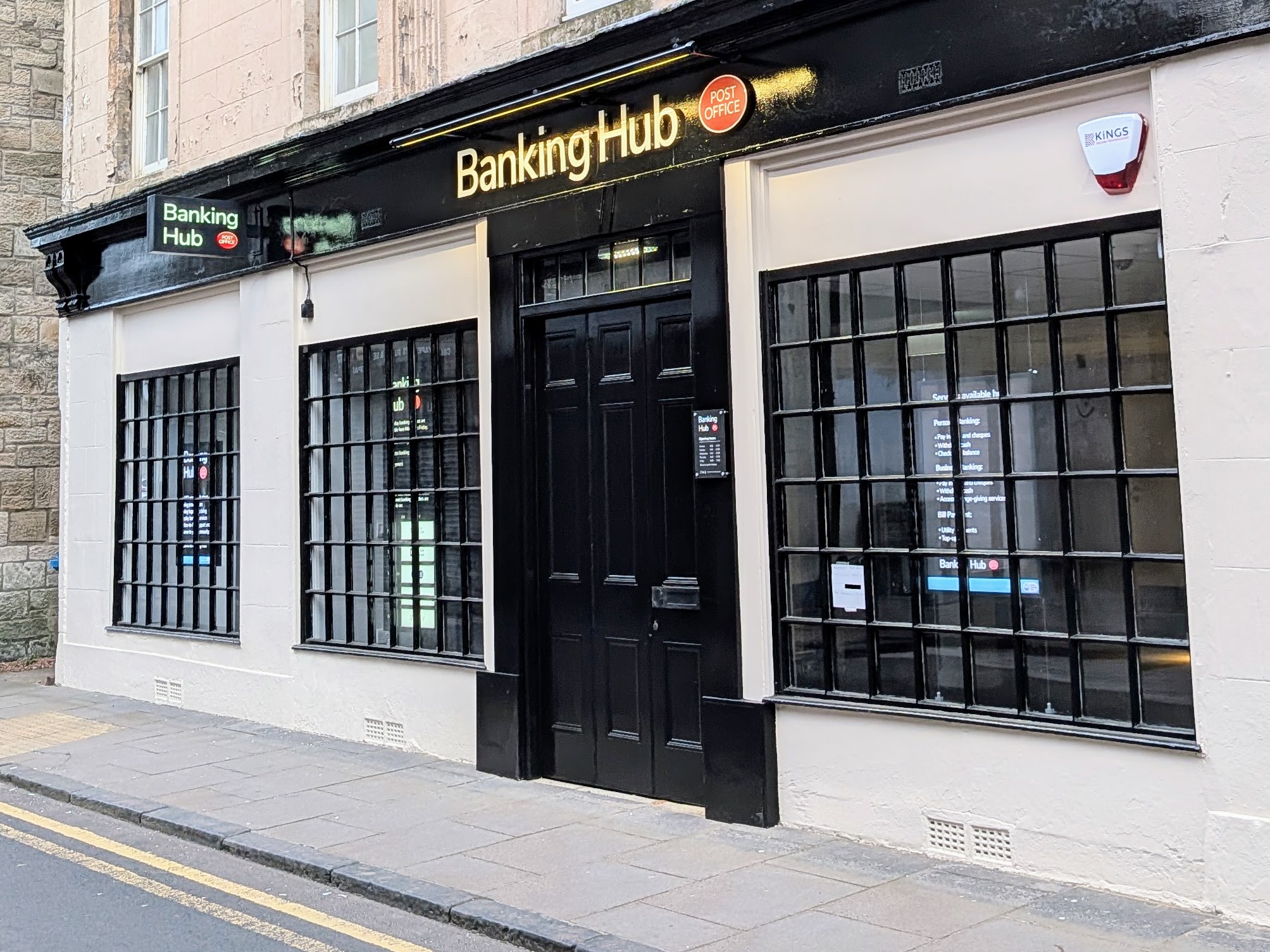 Exterior view of a Banking Hub building in Bo'ness, featuring large windows and a black door. The sign reads 'Banking Hub'.